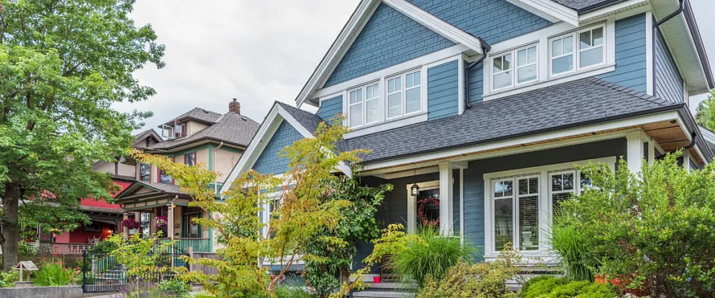 A modern two-story home with blue siding, white trim, and a well-maintained front yard.