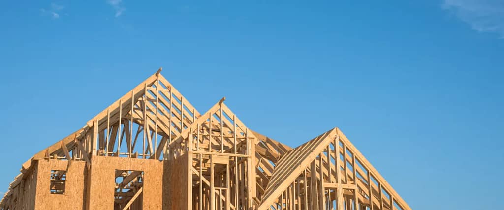 A wooden house frame under construction with clear blue sky in the background.
